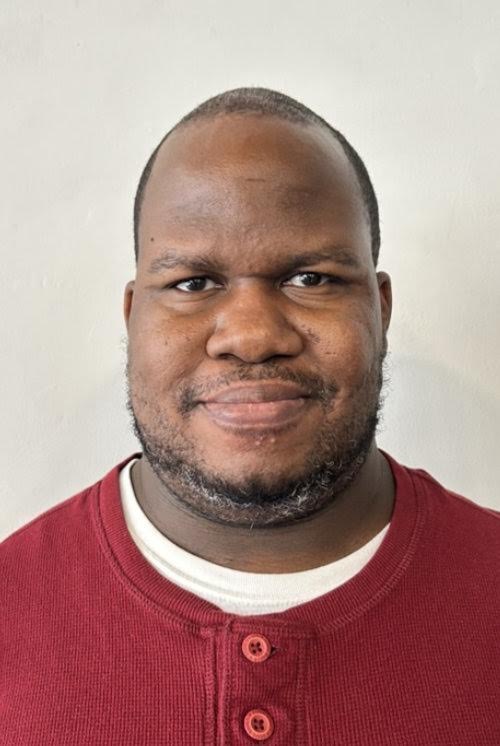 Photo of Tyrone Weedon in front of a beige wall.